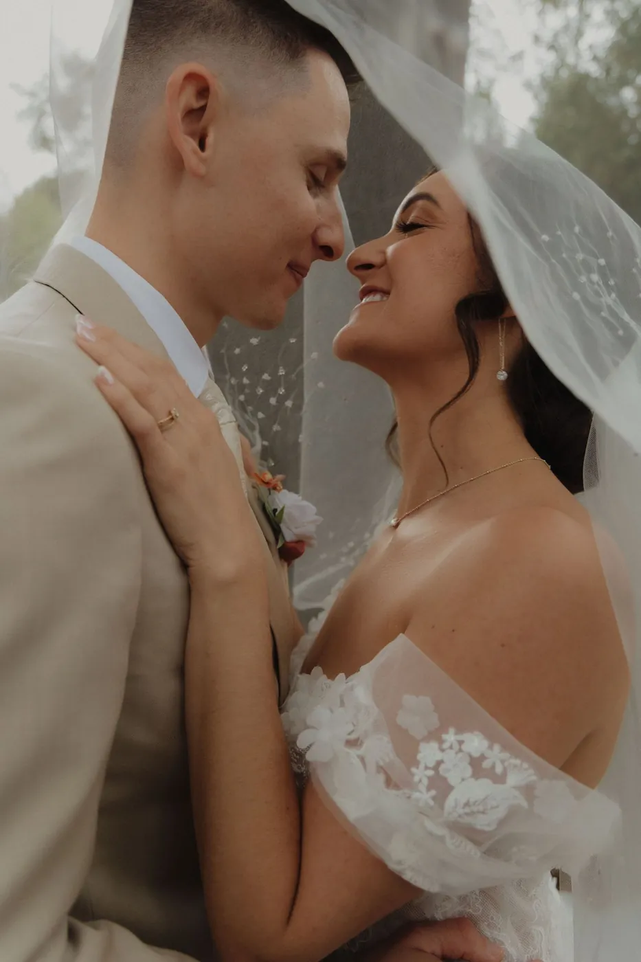 Bride and groom touching foreheads beneath her veil